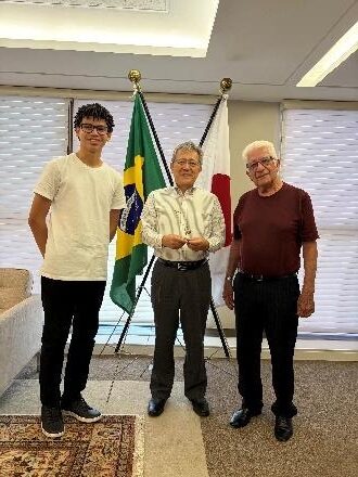 Artur Costa, Cônsul Masami Ohno e Dr. Odecil Oliveira em pé entre as bandeiras do Brasil e do Japão.